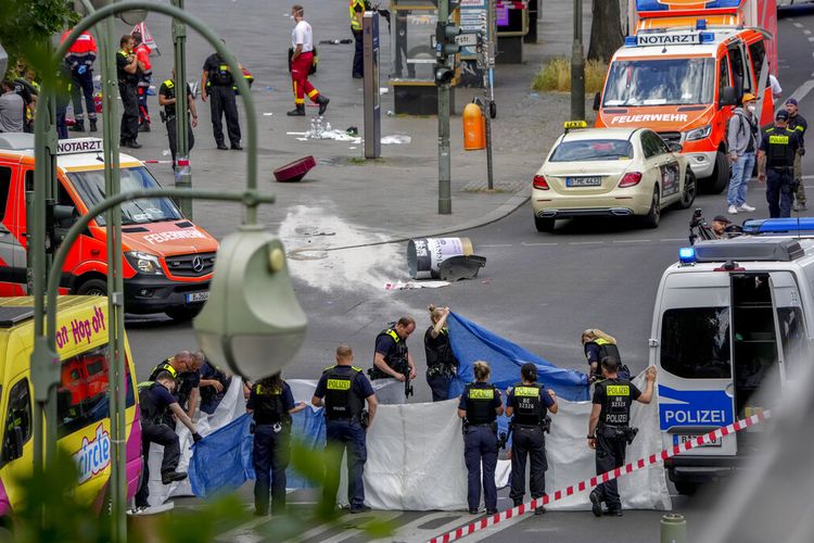 Petugas polisi menutupi mayat setelah sebuah mobil menabrak kerumunan orang di Berlin tengah, Jerman, Rabu, 8 Juni 2022. 
