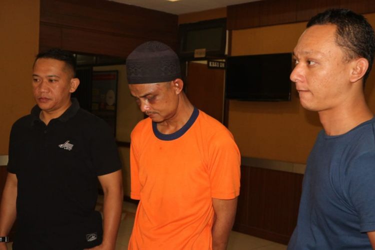 UR (42), orangtua yang tega mencabuli dua anak gadisnya sendiri saat di Mapolres Garut didampingi Kanit PPA Polres Garut (baju hitam)