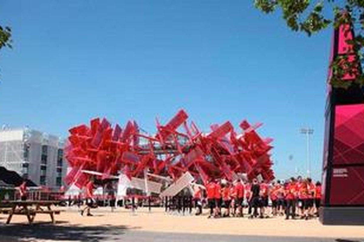 sekelompok pelajar berbaju merah berkumpul di depan sarana BeatBox di kompleks Olympic Park, London, Kamis (26/7/2012). Mereka adalah relawan yang akan mengisi acara seni di kompleks tersebut selama kegiatan pembukaan Olimpiade London 2012, Jumat (27/7/2012) malam.  