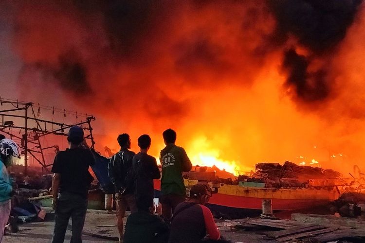 Warga melihat kapal yang terbakar di  Pelabuhan Perikanan Pantai (PPP) Tegalsari atau Pelabuhan Jongor, Kota Tegal, Jawa Tengah yang belum juga padam, Selasa (15/8/2023) malam.