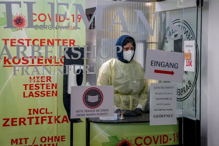 Seorang pekerja medis berdiri di depan pintu sebuah barbershop yang sebagian diubah menjadi test center di Frankfurt, Jerman, Senin, 15 November 2021. 