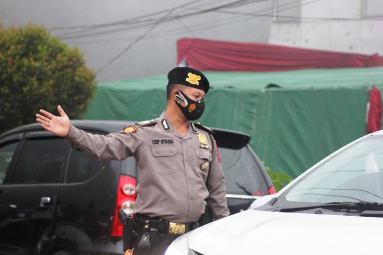 Seorang anggota olisi memutar balik kendaraan dari arah Bogor yang hendak menuju Cianjur di wilayah perbatasan Puncak Pass, Cianjur, Jawa Barat, Minggu (16/5/2021).