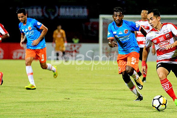 Gelandang Madura United, Slamet Nurcahyono, berupaya melewati hadangan pemain belakang Perseru Serui, Kelvin Wopi, dalam laga pekan ke-16 Liga 1 2018 di Stadion Ratu Pamellingan Pamekasan, Jawa Timur, Selasa (16/07/2018) malam.
