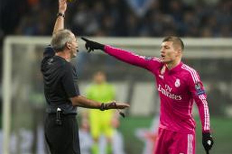 Gelandang Real Madrid, Toni Kroos (kanan), diganjar kartu kuning oleh wasit Martin Atkinson dalam pertandingan leg pertama babak 16 besar Liga Champions di Veltins Arena di Gelsenkirchen, Rabu (18/2/2015).