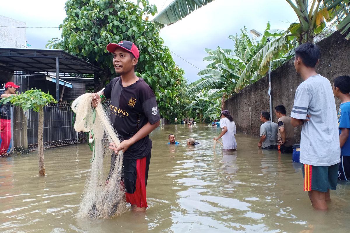 Beberapa warga terlihat menjala ikan di area banjir sekitar Danau Cipondoh