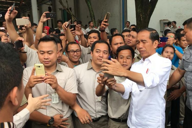 Momen ketika Presiden Joko Widodo kesulitan mencari fitur kamera pada ponsel milik warga yang meminta selfie dengan dia di Kabupaten Bandung, Jawa Barat, Minggu (10/3/2019).