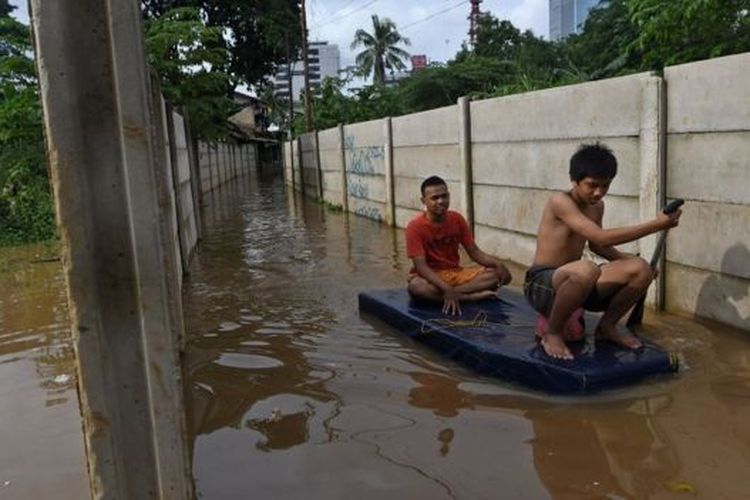 Warga menggunakan perahu buatannya untuk menyusuri jalan perkampungan yang tergenang banjir luapan air Sungai Ciliwung di Cawang, Jakarta, Kamis (20/02). 