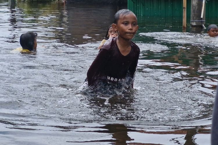 Anak-anak terdampak banjir di Genuksari, Kota Semarang bermain genangan banjir di sekitar rumah, Jumat (15/3/2024).