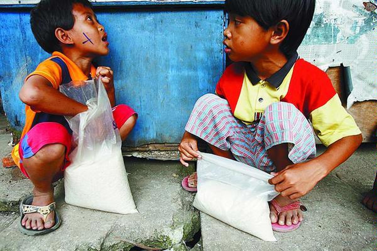 Rigal dan Nono beristirahat setelah mengumpulkan beras di Pasar Induk Beras Cipinang, Jakarta Timur, Selasa (18/3). Kedua anak ini sehari-harinya memulung beras yang tercecer dari karung yang digancu oleh para kuli panggul saat beras karungan itu akan diangkut atau diturunkan dari truk menuju ke toko atau pembeli.  