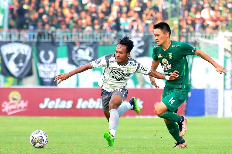 Pemain Persib Bandung Robi Darwis melewati pemain Persebaya Surabaya Sho Yamamoto saat pertandingan pekan ke-30 Liga 1 2022-2023 yang berakhir dengan skor 2-2 di Stadion Gelora Joko Samudro Gresik, Senin (13/3/2023) sore.