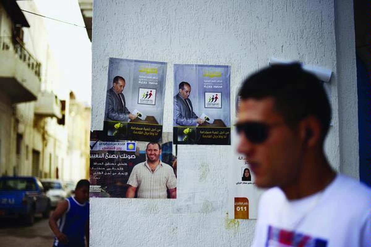 Seorang warga Libya berjalan melewati poster Mahmud Jibril, pemimpin Koalisi Kekuatan Nasionalis (NFA),  setelah pencoblosan,  di Tripoli, Minggu (8/7). Kelompok liberal mengklaim memimpin perolehan suara pada pemilu pertama pasca-lengsernya pemimpin Libya Moammar Khadafy dan mendapat sambutan dari komunitas internasional.