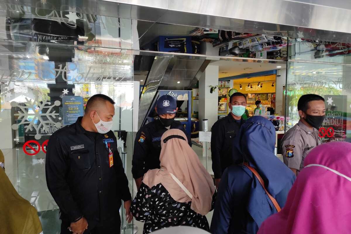 MASUK MALL—Pengunjung yang masuk ke Plaza Mall Kota Madiun menunjukkan aplikasi peduli lindungi kepada petugas, Rabu (8/9/2021).