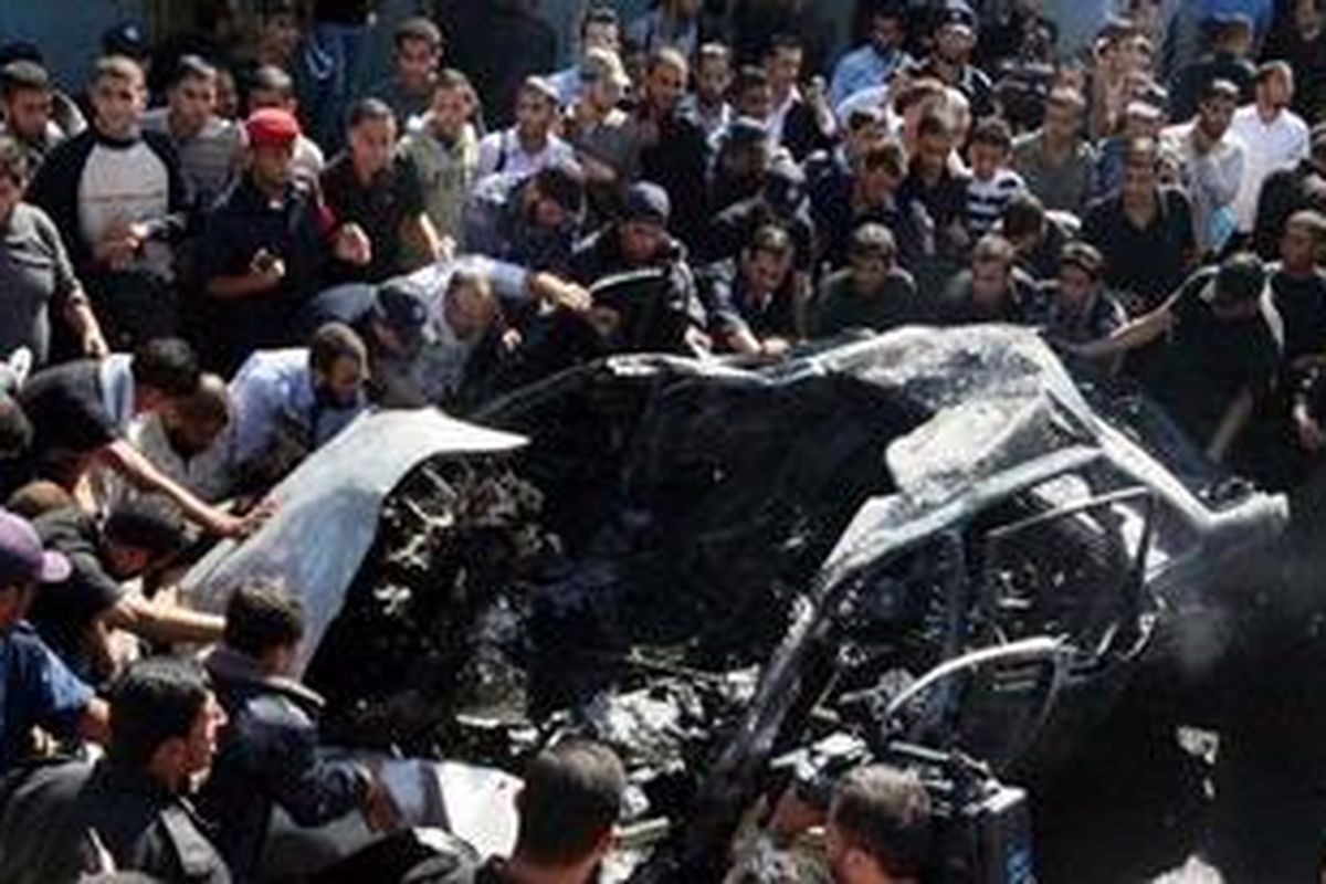 Warga Gaza mengerumuni mobil yang meledak dekat markas kepolisian. Belum jelas penyebab ledakan meski Hamas telah menuduh serangan udara Israel penyebabnya. 