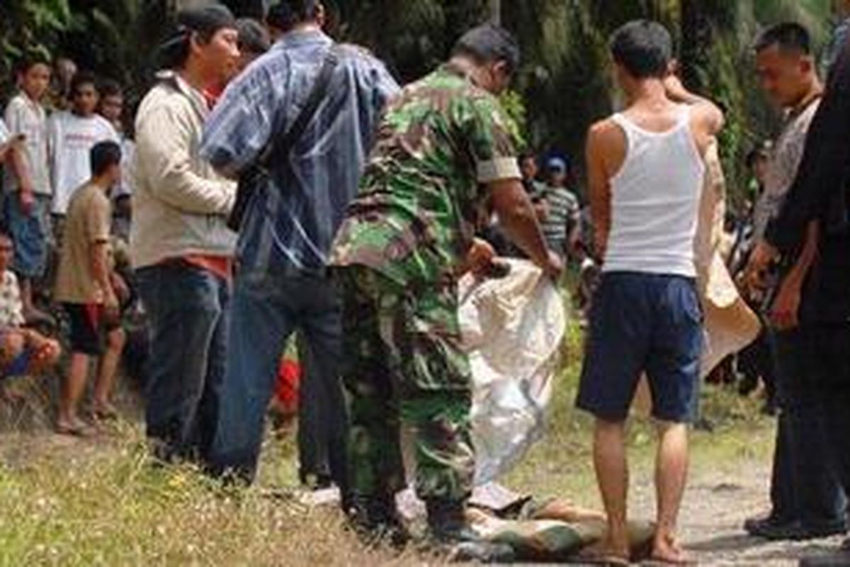 Polisi menutupi jenazah  salah satu tersangka yang tewas dalam baku tembak di  perkebunan kelapa sawit Dusun III Pondok Sebrang, Desa Martebing, Kecamatan Dolok Masihul, Serdang Bedagai, Sumut Minggu (3/10/2010). 