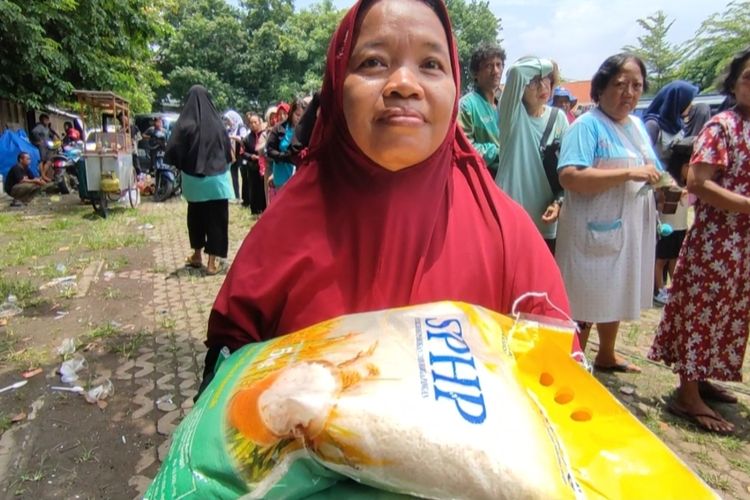 Tini (37) warga Kesambi Kota Cirebon berkerudung merah, menunjukan beras SPHP yang dia dapat stelah mengantre Berjam jam untuk mendapatkan beras murah di lapangan Kesambi pada Rabu (21/2/2024) siang