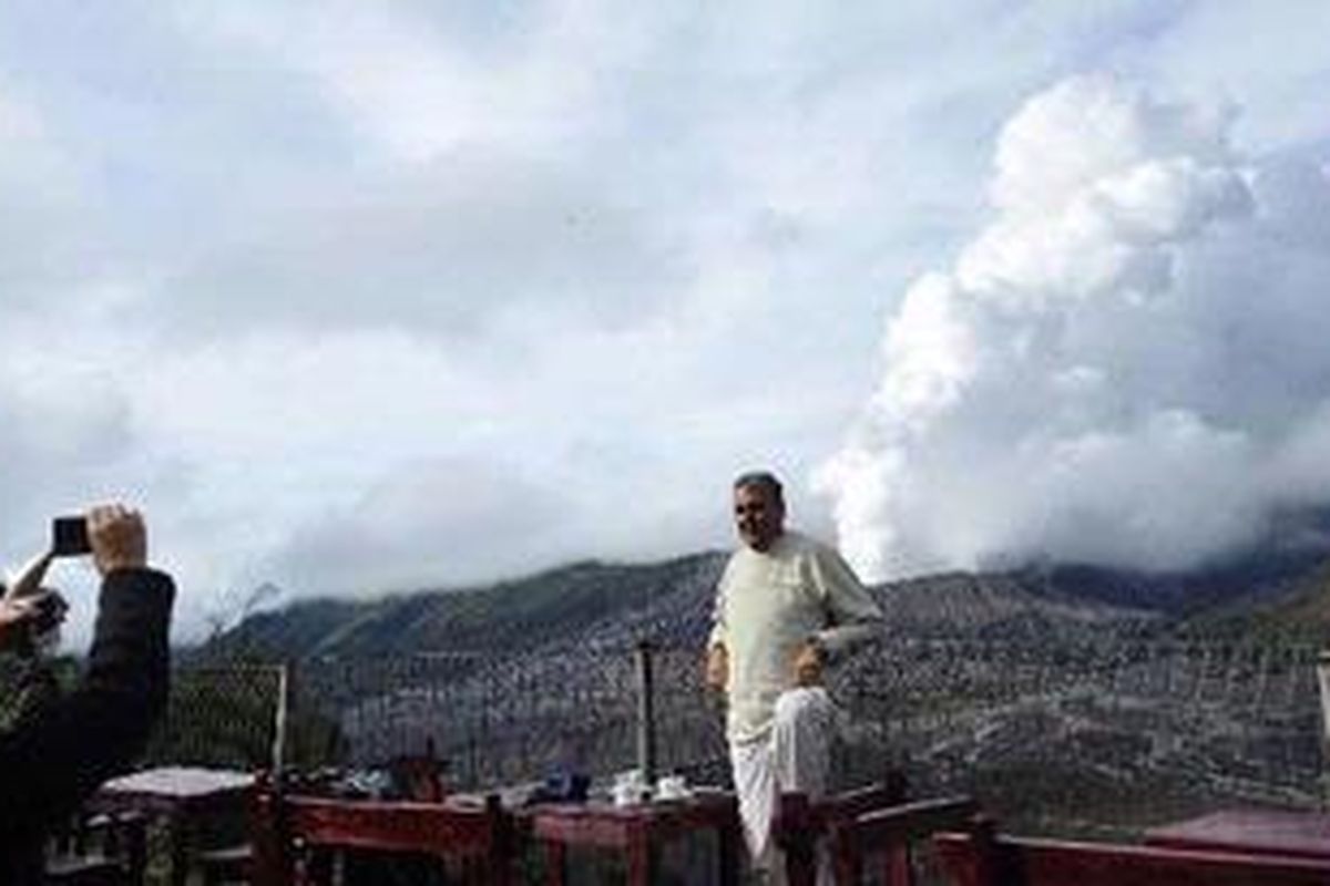 Wisatawan berfoto dengan latar Gunung Bromo yang mengeluarkan asap sulfatara di Desa Ngadisari, Sukapura, Probolinggo, Kamis (25/11/2010). Wisatawan dan warga dilarang untuk mendekati kawah bromo dengan radius tiga kilometer.