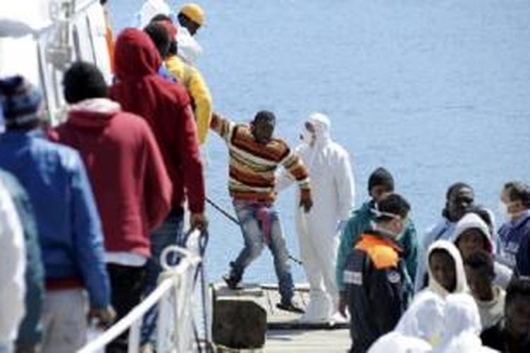 Para imigran diturunkan dari sebuah kapal patroli Italia di Palermo. 