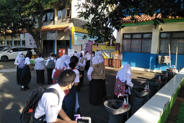 Siswa SMPN 3 Depok terapkan protokol kesehatan dengan mencuci tangan dan scan barcode pedulilindungi sebelum masuk kelas, Senin (24/1/2022).