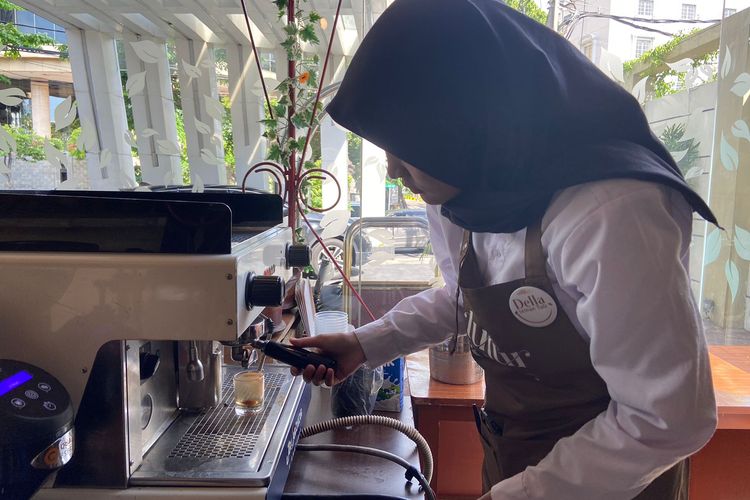 Della (20) barista tuli saat menyeduhkan kopi dari mesin di Kopi Tutur Rasa, Surabaya. 