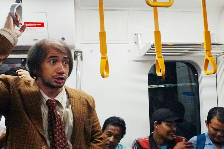Artis peran Reza Rahadian memakai kostum karakter Bossman di film My Stupid Boss 2 diabadikan saat menyapa penumpang MRT rute Bundaran HI-Lebak Bulus, Jumat (29/3/2019).