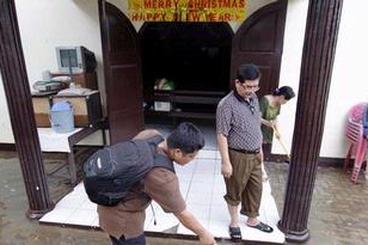 Jemaat menyapu genangan air yang ada di pelataran Gereja HKBP MT Haryono, Bidaracina, Jakarta Timur, Senin (24/12/2012). Akibat banjir, umat kristiani yang merupakan jemaat gereja terancam batal mengikuti misa malam Natal karena sisa banjir yang masih dalam proses pembersihan.
