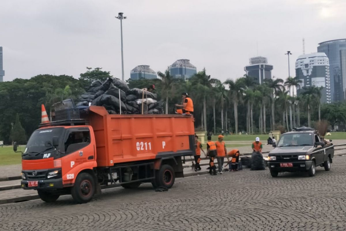 Petugas kebersihan kawasan Monas dan pasukan oranye Dinas Lingkungan Hidup bergotong royong membersihkan sampah setelah kegiatan Reuni 212 di kawasan Monas dan sekitarnya, Jakarta Pusat, Minggu (2/12/2018).