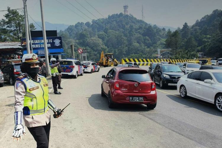 Polisi tengah mengatur arus kendaraan yang memasuki kawasan Puncak Cianjur, Jawa Barat. Diprediksi volume kendaraan melonjak drastis pada libur panjang akhir pekan ini.