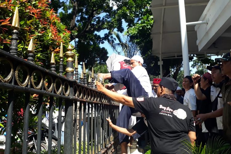 Massa pro-Gubernur DKI Jakarta Anies Baswedan memanjat pagar saat berdemo di Balai Kota DKI Jakarta, Selasa (14/1/2020).