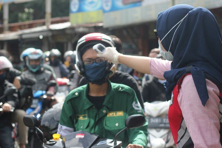 Petugas gabungan memeriksa suhu tubuh pengendara di check point 1 Segar Alam Ciloto, Cianjur, Jawa Barat yang hendak masuk ke wilayah Cianjur.