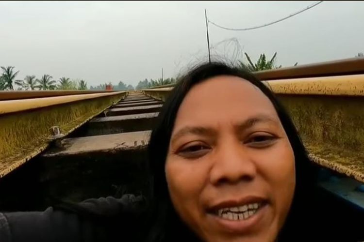 Tangkapan layar video viral youtuber Dede Inoen sembunyi di kolong rel saat kereta melintas.