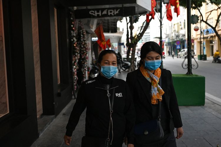 Dua wanita mengenakan masker untuk melindungi diri dari Covid-19, berjalan di jalanan Hanoi, Vietnam, pada 29 Januari 2021,sehari setelah negara itu mengumumkan kasus pertama dalam dua bulan.