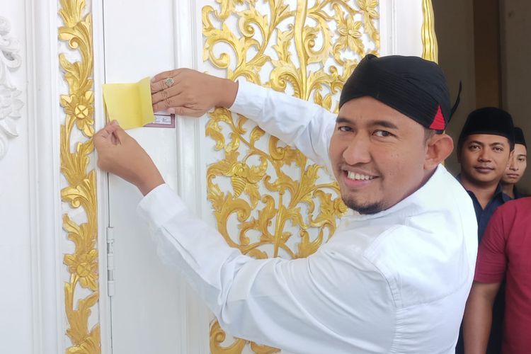 Bupati Sumenep, Achmad Fauzi saat menempel stiker coklit di depan pintu rumahnya, Senin (20/2/2023). 