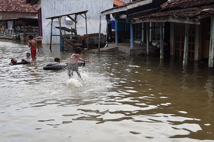 Anak-anak yang bermain di jalan yang tergenang rob. KOMPAS.COM/SLAMET PRIYATIN