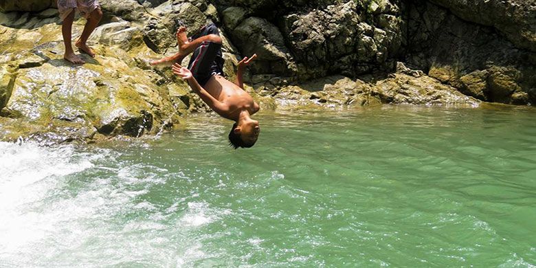 Seorang anak sedang salto di kolam alami Taman Sidandang, Purworejo.