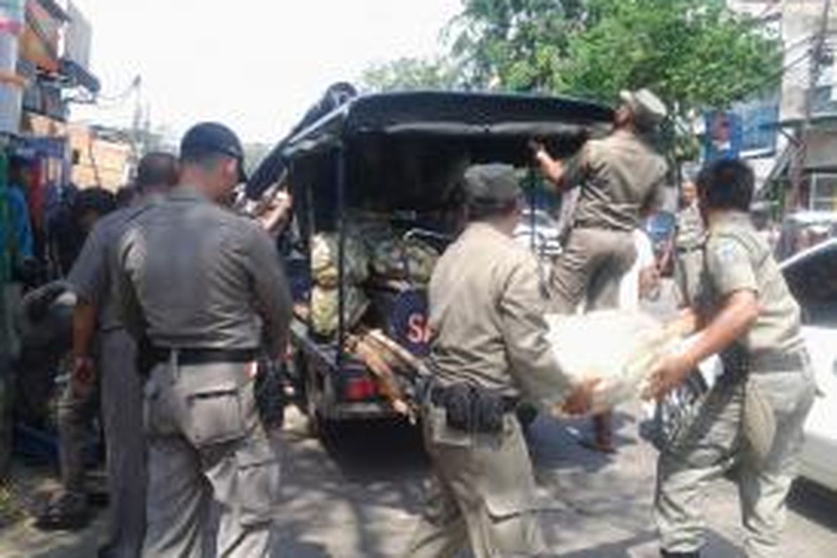 Petugas Satpol PP Jakarta Barat menertibkan barang-barang pedagang kaki lima (PKL) yang berjualan di badan Jalan KH Moh Mansyur, Tambora, Jakarta Barat, Selasa (15/7/2014).