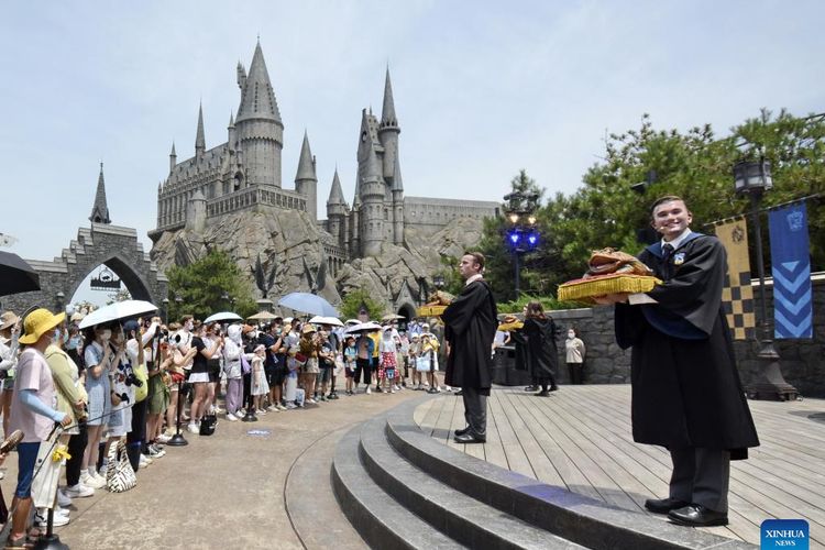 Turis menyaksikan atraksi di Universal Studios Beijing, Sabtu (25/06/2022). Taman bermain ini sempat tutup sementara selama lebih kurang dua bulan karena kenaikan kasus Covid-19.