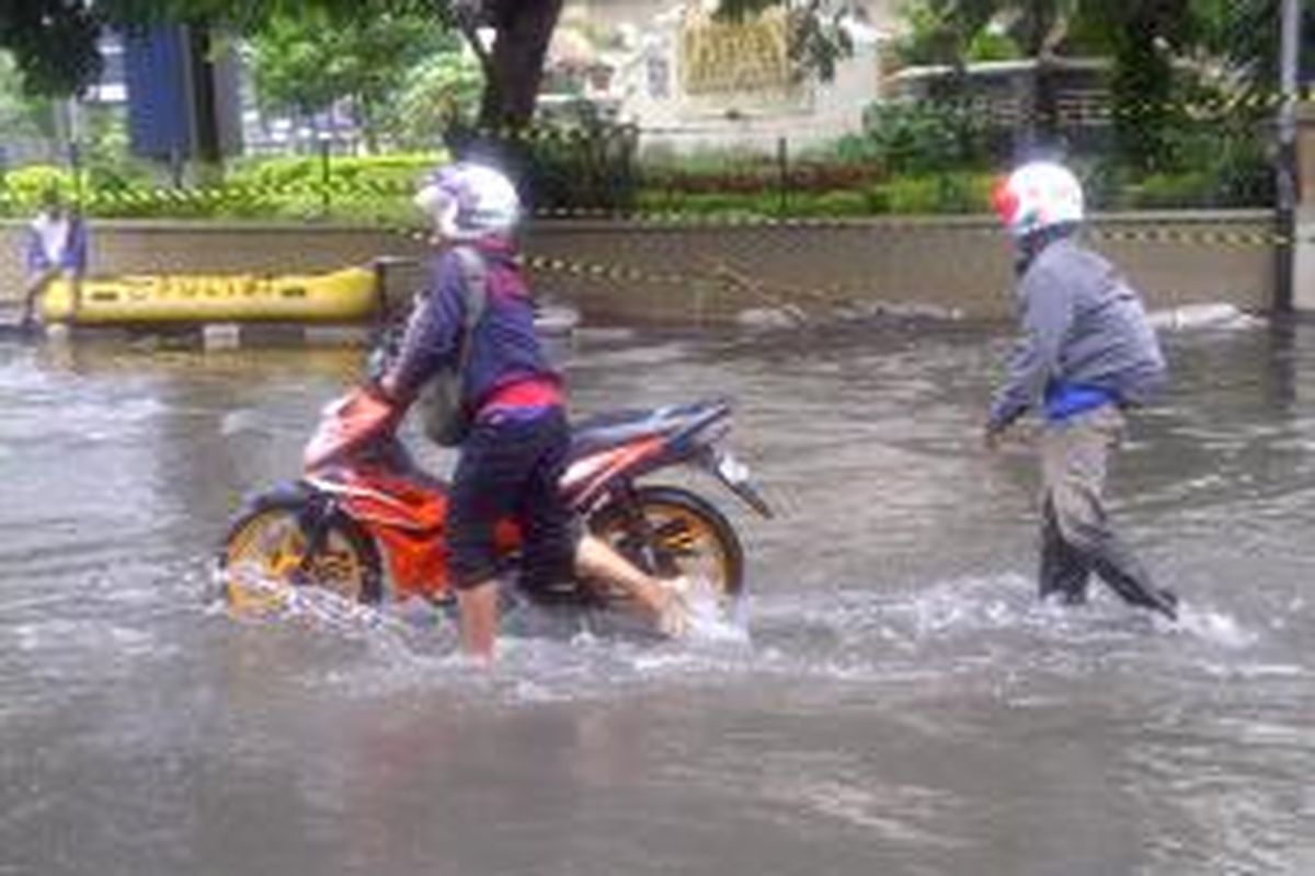 Warga mencoba mendorong sepeda motor miliknya di Jalan Tanjung Duren, Jakarta Barat, Rabu (29/1/2014). Banjir setinggi paha orang dewasa mengakibatkan sejumlah kendaraan sulit melintas.