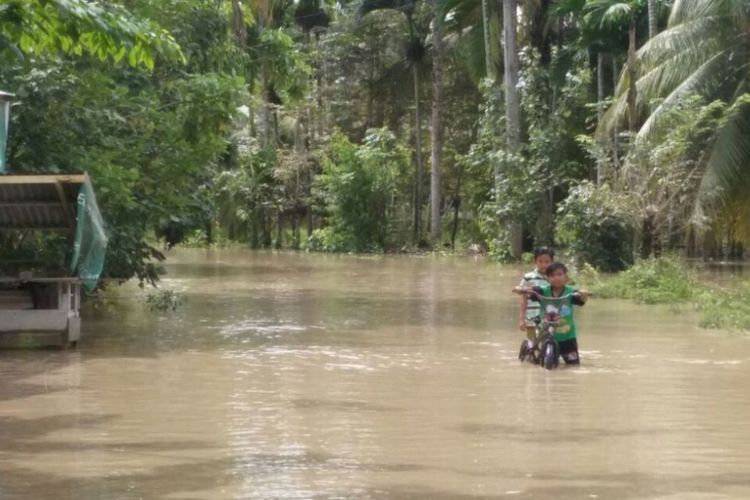 Seorang anak melintas di jalanan banjir Desa Alue Thoe, Kecamatan Matangkuli, Aceh Utara, Jumat (10/11/2017)