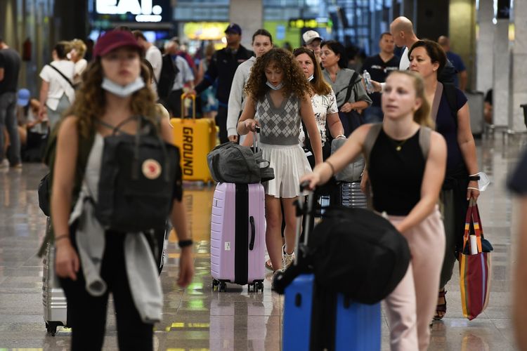 Para penumpang pesawat terbang sedang berjalan di Terminal 2 Bandara El Prat di Barcelona, Spanyol. Pada periode musim panas terjadi kenaikan angka lalu lintas penerbangan.