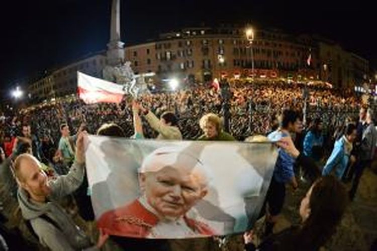 Sejumlah peziarah Katolik memegang foto mendiang Paus Yohanes Paulus II yang meninggal dunia sembilan tahun lalu di jalanan kota Roma tak jauh dari Vatikan. Paus Fransiskus dijadwalkan memimpin upacara kanonisasi Paus Yohanes XXIII dan Paus Yohanes Paulus II pada Minggu (27/4/2014).