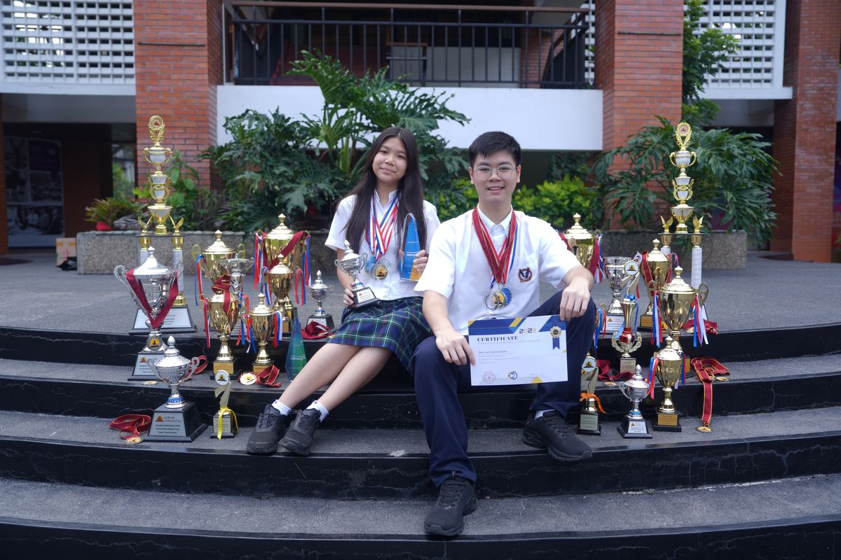 (ki-ka) Ava Mikayla Emmanoelle Kasih (14) dan Sean Levi Danuseputra (15) tengah berpose dengan memakai medali, dikelilingi piala, dan memegang sertifikat kompetisi mereka.
