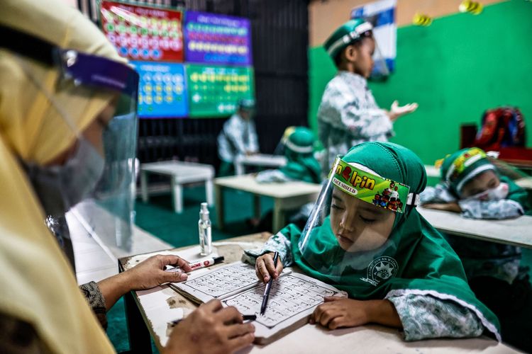 Guru menggunakan masker dan pelindung wajah saat menerangkan pelajaran dalam kelas tatap muka di TK An-Nuur, Jakarta Selatan, Selasa (4/8/2020). Uji coba pembelajaran tatap muka ini berlangsung dengan menjalankan protokol kesehatan Covid-19.