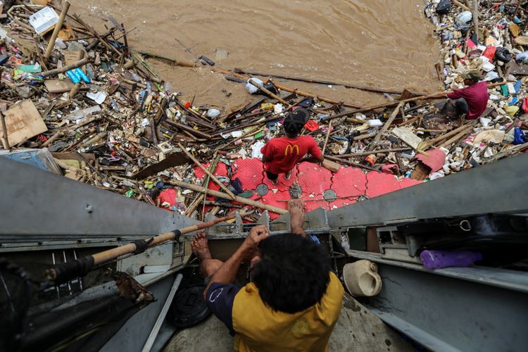 Warga menggambil barang-barang berharga yang terbawa arus di Pintu Air Manggarai, Jakarta, Rabu (7/2/2018). Dinas Lingkungan Hidup dan Kebersihan DKI Jakarta telah mengangkut 1.596 ton sampah yang hanyut akibat air kiriman dari Bendungan Katulampa, Bogor pasca banjir yang melanda Jakarta.