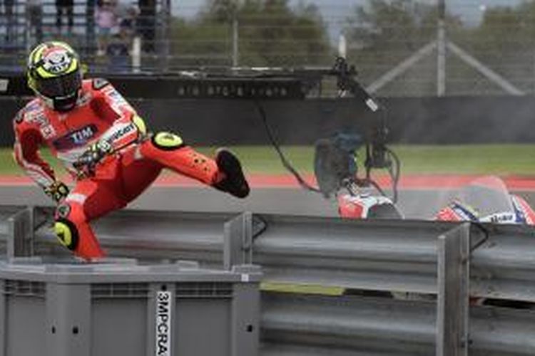 Pebalap Ducati asal Italia, Andrea Iannone, melompati pagar pembatas lintasan setelah mengalami kerusakan mesin saat turun pada sesi latihan bebas pertama GP Argentina di Sirkuit Termas de Rio Hondo, Jumat (17/4/2015).