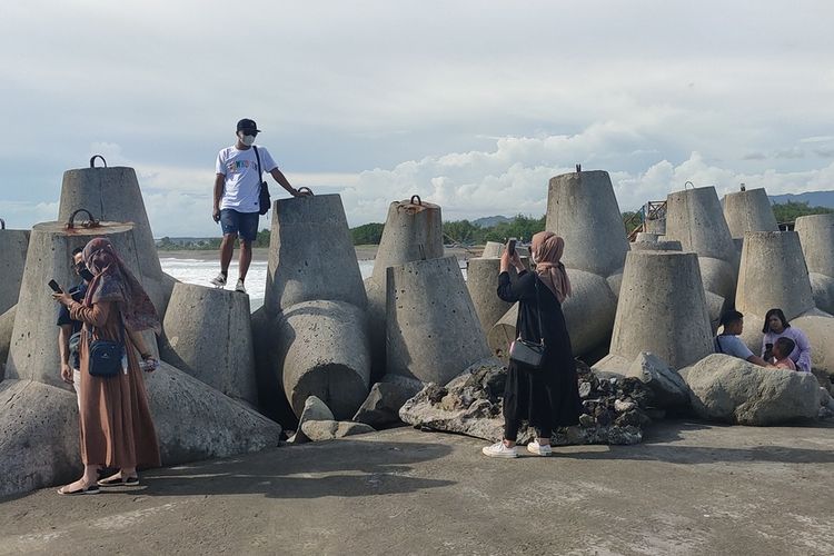 Pengunjung yang bermain di Pantai Wisata Glagah di Kabupaten Kulon Progo, Daerah Istimewa Yogyakarta, Minggu (26/12/2021). Pantai ini punya garis pantai lurus dan indah. Pemecah ombak terdiri dari beton kaki empat juga jadi sudut foto yang disukai pengunjung.