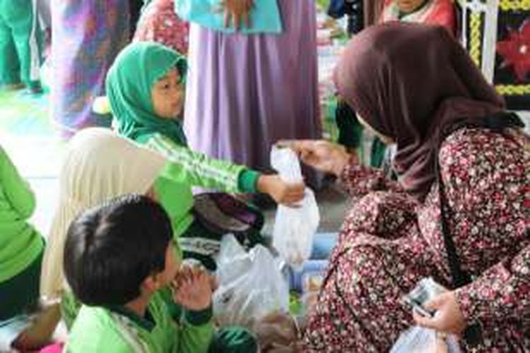 Seorang pengunjung sedang membeli jajanan kepada para pedagang cilik yang merupakan siswa PAUD TK IT Az Zahra, Takengon, Aceh Tengah, Aceh, Sabtu (5/3/2016).