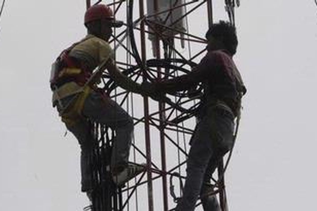 Petugas memperbaiki menara BTS. 