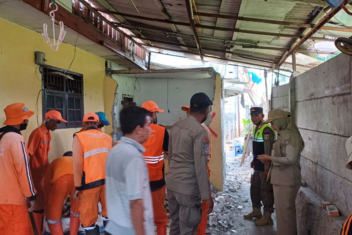 Petugas gabungan tengah membantu salah satu warga saat rumahnya diterbitkan karena berdiri di atas saluran air, Selasa (21/11/2023).