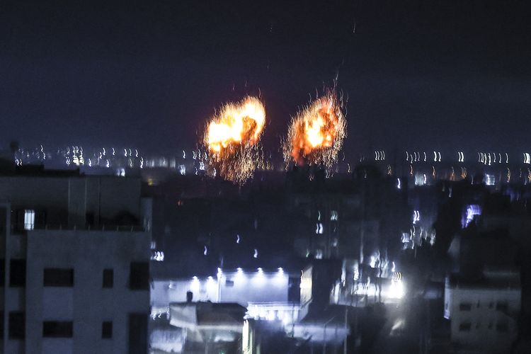 Ledakan menerangi langit malam di atas gedung-gedung di Kota Gaza saat pasukan Israel menembaki daerah kantong Palestina, pada awal 16 Juni 2021.