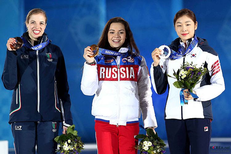 Tiga atlet figure skating atau seluncur indah dalam Olimpiade Musim Dingin 2014 di Sochi, Rusia. Karolina Kostner (kiri), Adelina Sotnikova (tengah), dan Yuna Kim (kanan).